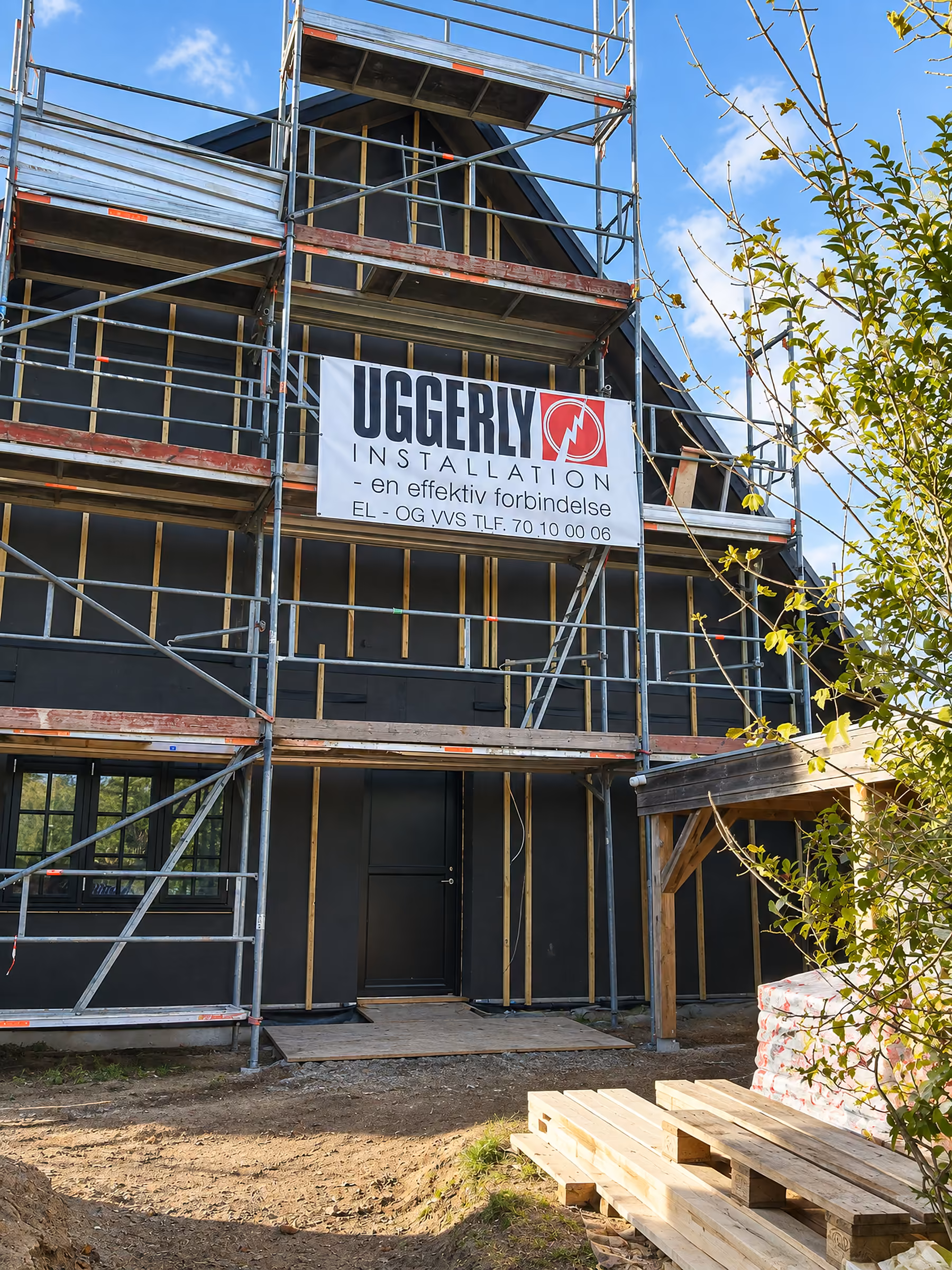 Byggepladsbanner med Uggerly Installation på stilladset ved et hus under renovering