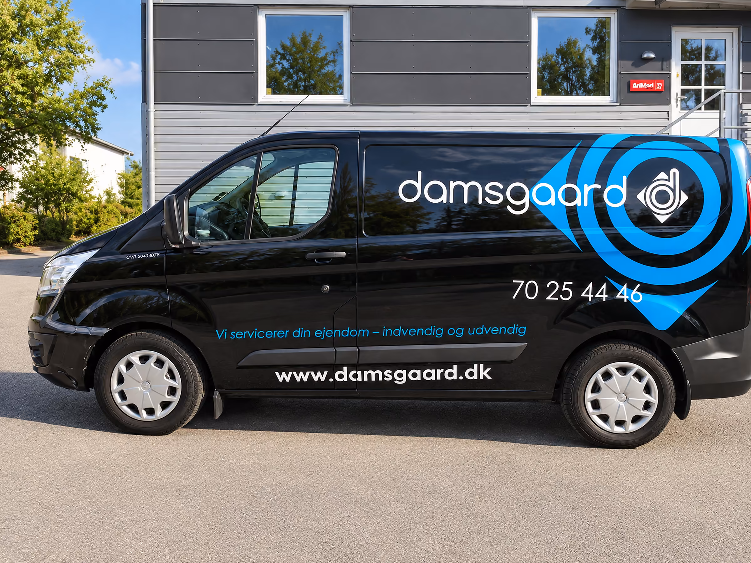 Bilreklame på Damsgaards sorte Ford Transit Custom med logo, slogan og cirkelgrafik