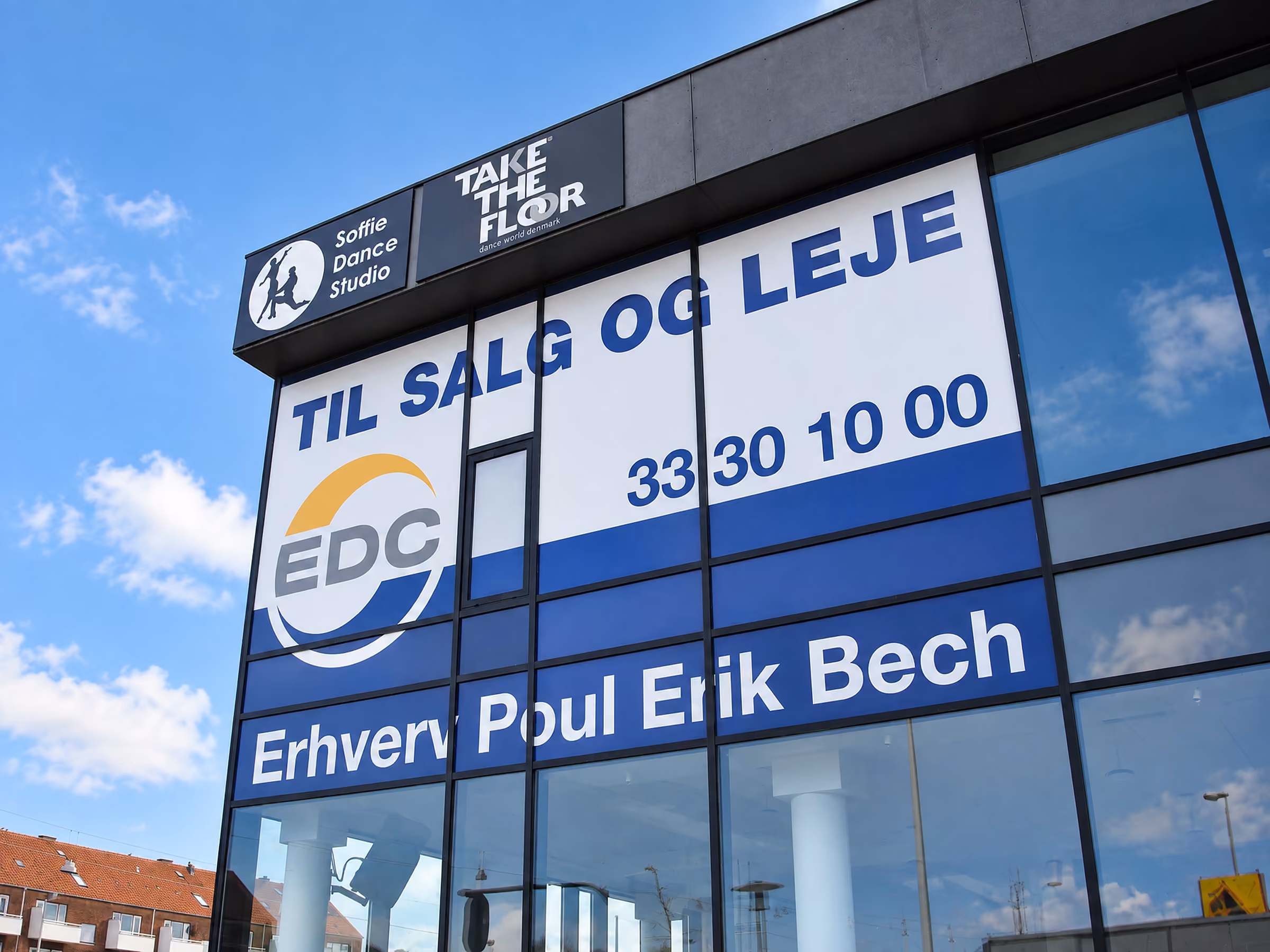 Stort banner TIL SALG OG LEJE fra EDC Erhverv Poul Erik Bech på en kontorbygning