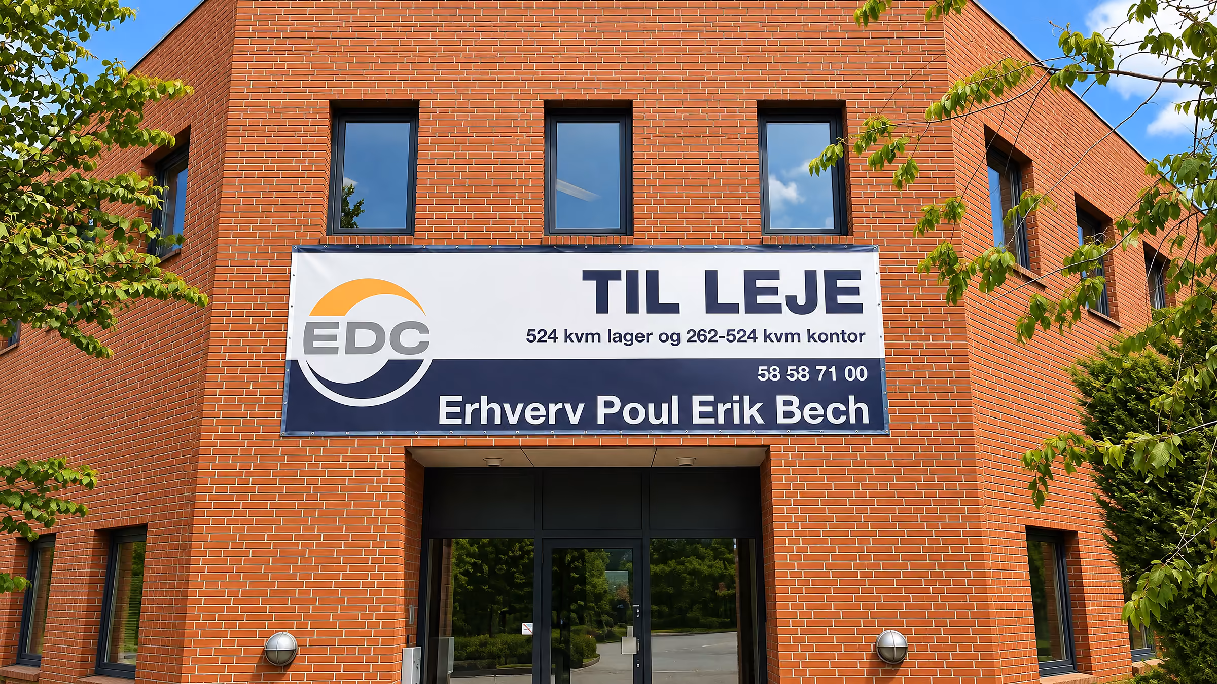 TIL LEJE-banner over indgangen til en erhvervsbygning i røde mursten