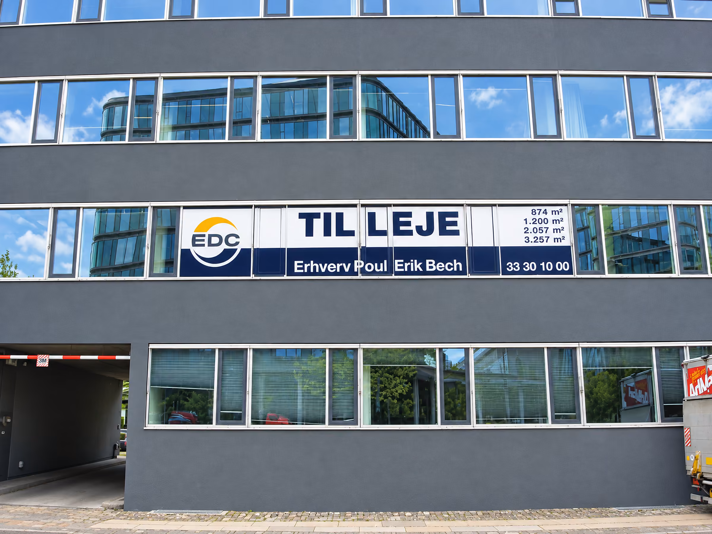 Langt TIL LEJE-banner fra EDC Erhverv hen over en kontorfacade