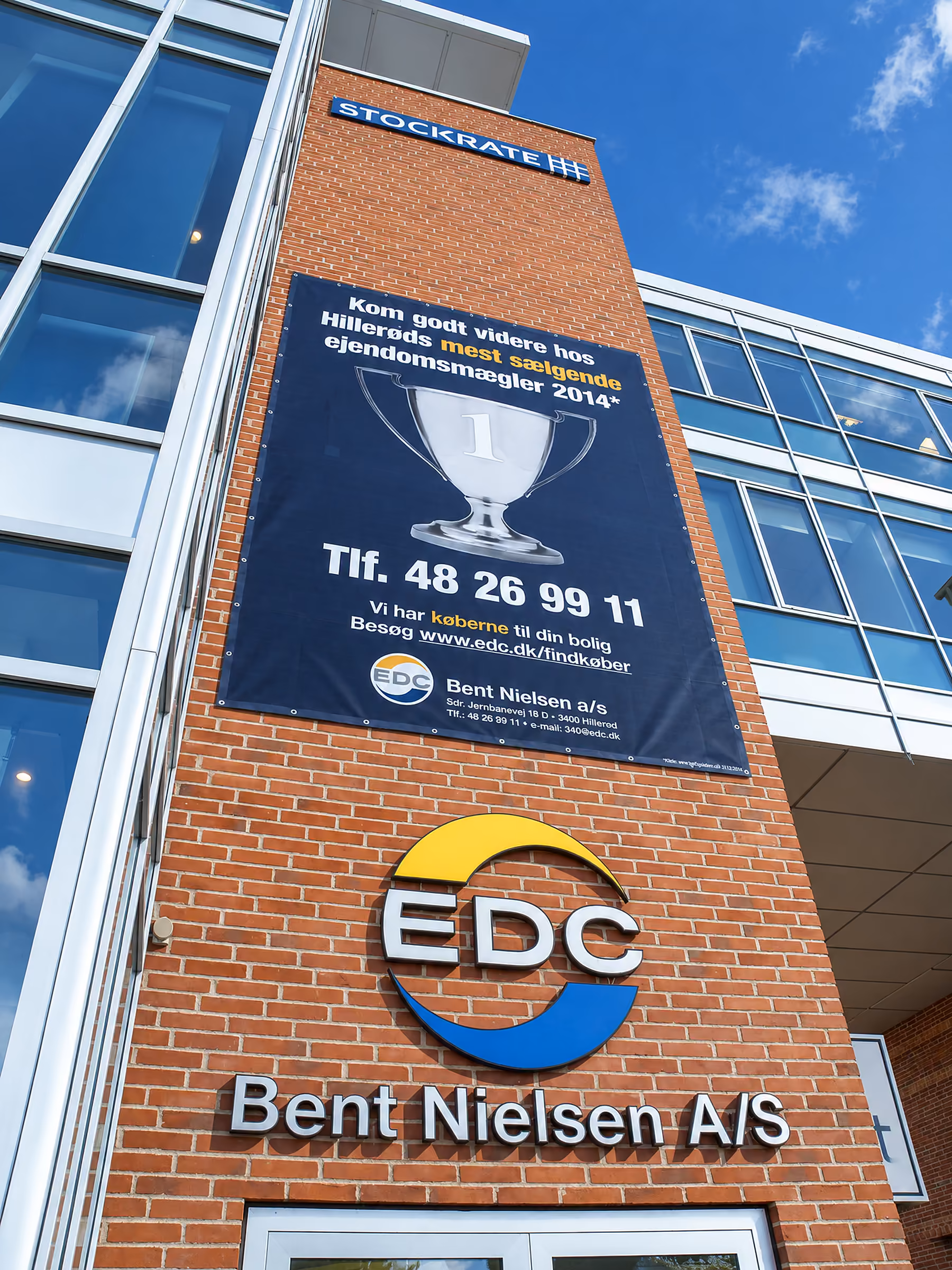 Lodret banner og EDC-logo på et kontortårn i røde mursten