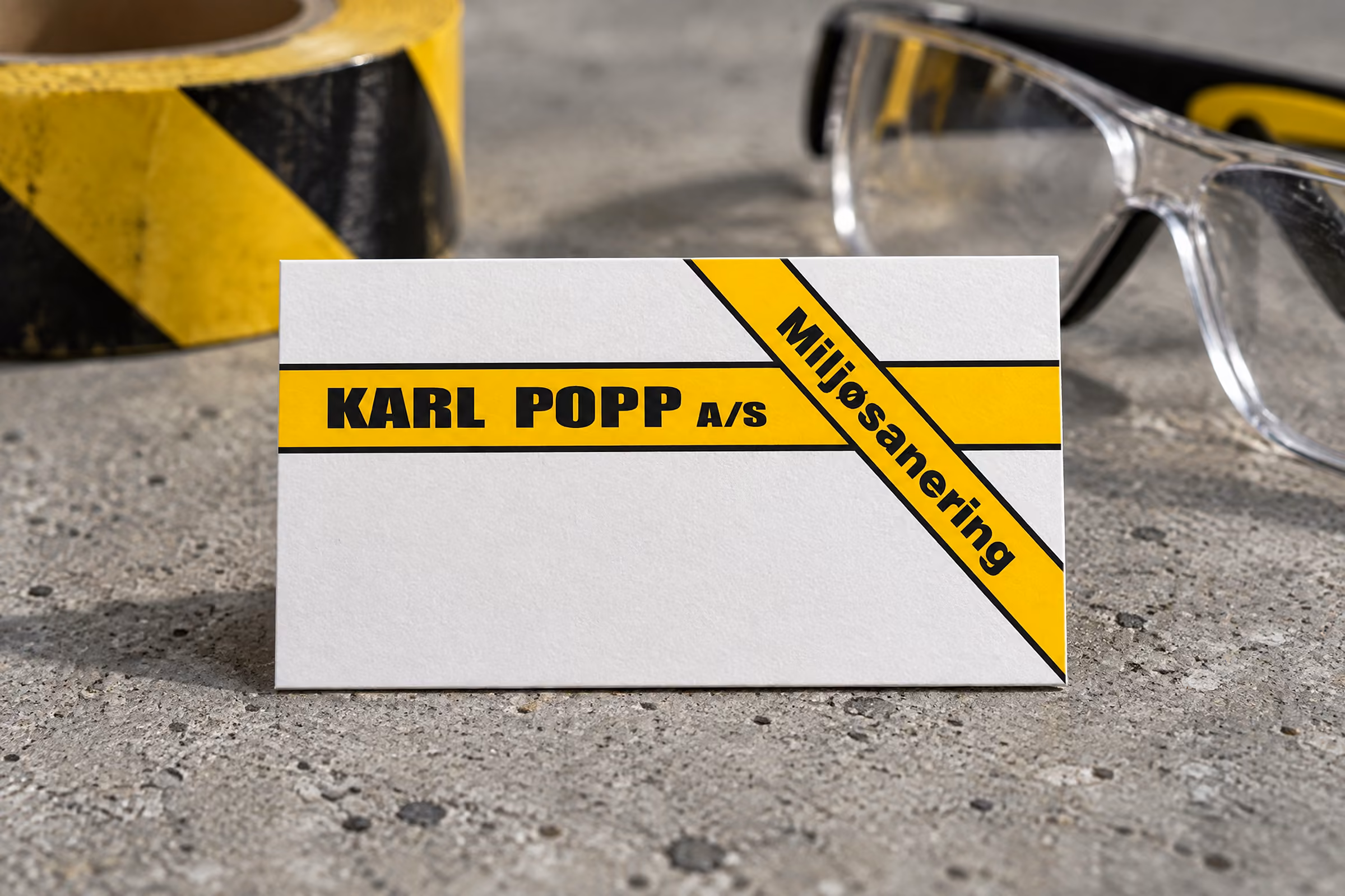 Karl Popps logo med det gule miljøsaneringsbånd på et visitkort