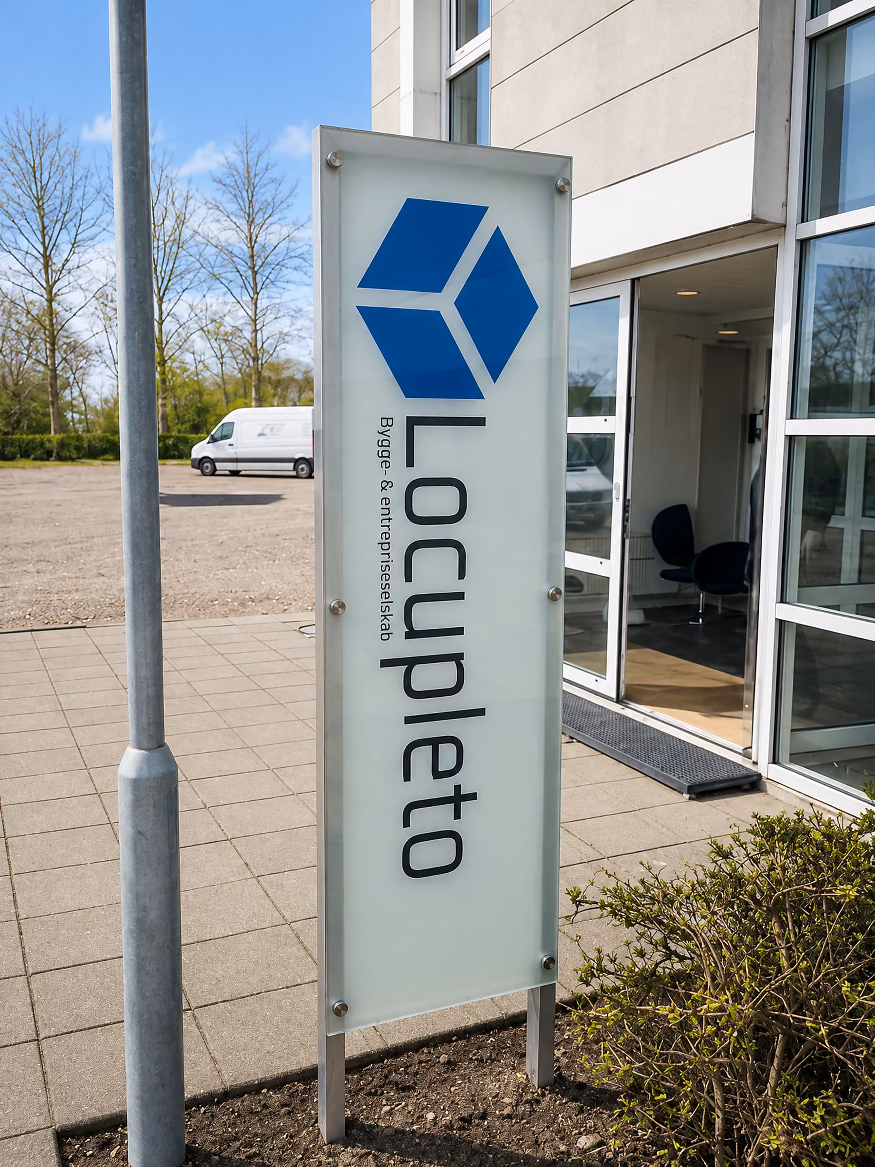 Monteret glaspylon med Locupletos logo foran kontorbygningen