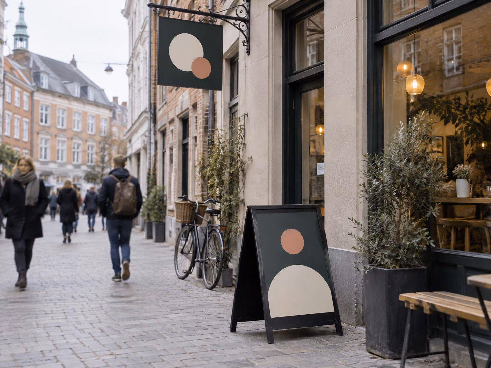 Illustration af A-skilt på fortovet og udhængsskilt over fortovet i en dansk gågade